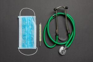 Top view of stethoscope, medical protective mask and thermometer on colorful background. Medical accessories concept photo