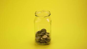 Zeit Ablauf von Geld Münze im Glas Flasche wachsend Wachstum Speichern Geld. Konzept finanziell Geschäft Investition. Gelb Hintergrund. 4k video