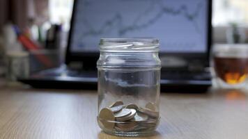 tid upphöra pengar mynt i en glas burk växer på de bakgrund av finansiell diagram. begrepp finansiell företag investering. närbild 4k video