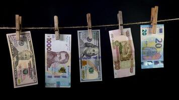 Banknotes of different countries dry on a clothespin rope on a black background. Money laundering concept. video