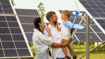 familia con solar paneles, renovable energía concepto. padres y bebé hijo jugando juntos con juguete aviones cerca solar paneles video