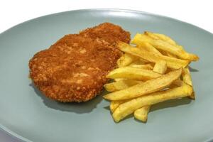 Breaded steak with french fries,  served on a turquoise plate. Isolated on a white background. photo