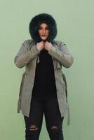 a woman in a fur hat with long green coat and black pants photo