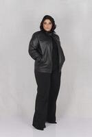 un mujer en un negro cuero chaqueta y negro pantalones foto