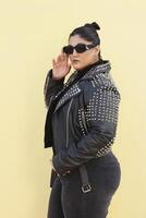 a woman in a black jacket and black sunglasses posing with bun photo