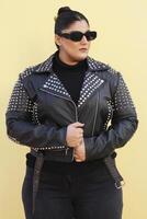 a woman in a black jacket and black sunglasses posing with bun photo