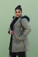 a woman in a fur hat with long green coat and black pants photo