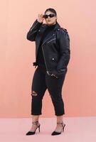 a woman in a black leather jacket and jeans posing for picture with glasses photo