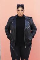 a woman in a black leather jacket and jeans posing for picture with glasses photo