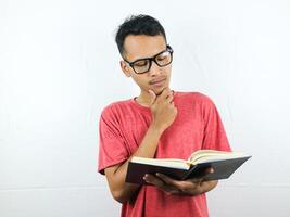 retrato de asiático hombre participación libro con pensando cara expresión foto