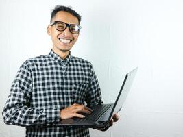 retrato de un asiático hombre participación un ordenador portátil con un sonriente cara expresión. publicidad concepto. foto