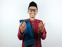 Religious asian muslim man in traditional dress using prayer beads isolated on white background photo