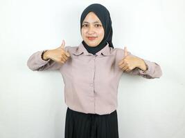 Smiling asian muslim woman in hijab showing thumb up in approval, recommending, like something good photo