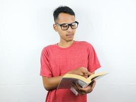 portrait of asian man holding book with reading focused expression. photo