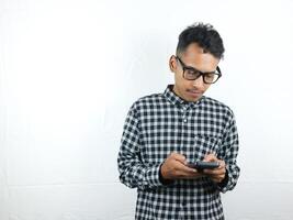retrato de asiático hombre participación móvil teléfono lectura, mecanografía mensaje con atención cara expresión. foto
