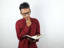 Portrait of Asian man holding book with thinking face expression photo