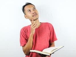 Portrait of Asian man holding book with thinking face expression photo