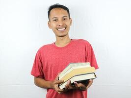 portrait of an asian man smiling and holding stack of books, isolated on white background. photo