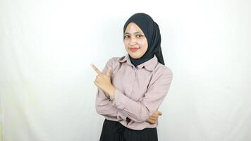 Beautiful Asian Muslim woman in hijab, smiling pointing fingers a side at copy space. photo