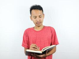 portrait of an asian man holding pen and writing book isolated on white background. photo