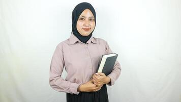 sonriente joven asiático musulmán estudiante participación libro, mirando a cámara aislado en blanco antecedentes. foto