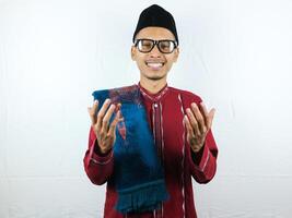 Religious asian muslim man in traditional dress using prayer beads isolated on white background photo