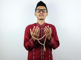 Religious asian muslim man in traditional dress using prayer beads isolated on white background photo