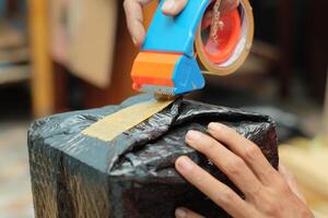 Men wrapping a package using cardboard, bubble wrap, and duct tape. Goods delivery process. photo