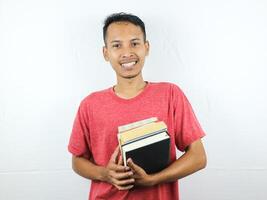 portrait of an asian man smiling and holding stack of books, isolated on white background. photo