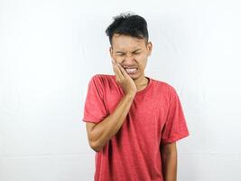 Adult Asian man touching his jaw, feeling toothache isolated on white background photo