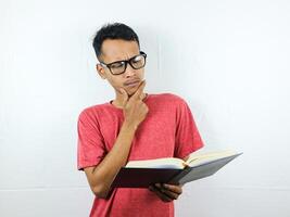 Portrait of Asian man holding book with thinking face expression photo