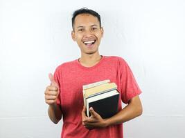 retrato de un asiático hombre sonriente y participación apilar de libros, aislado en blanco antecedentes. foto