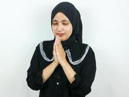 Young Muslim Asian woman praying, closing eyes Isolated on white background photo