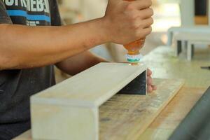 carpintero medición, corte, lijado de madera en taller foto