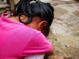 A little girl aged 3-4 years lowered her head and covered her face with her hands. Concept photo of social problems, family, violence against children and child abuse.