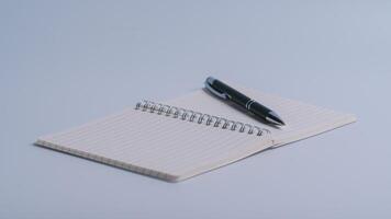 cuaderno y bolígrafo cerca arriba con un borroso antecedentes en el primer plano en blanco mesa antecedentes foto