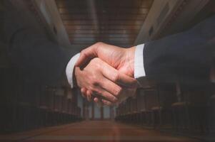 men or business people shaking hands with partner to greeting or dealing business joint venture with blurred seminar room photo