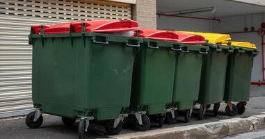 Heavy commercial rubbish bins on street kerbside. Big full garbage trash. Waste management industry removal contract concept photo