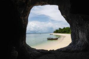 seascape beach view form the cave hole in southern Thailand with Traditional Long tail boat in background photo