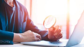 Searching opportunity businessman looking through a magnifying glass to documents. Business assessment and audit. Magnifying glass on a financial report photo