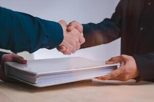 Hand shake concept, businessman is shaking their hands together and holding document folder for greeting dealing business join venture or investment in successful business photo