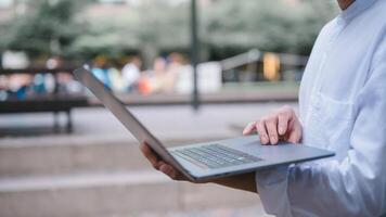 a businessman or freelancer using computer laptop sitting on table outside working on business or internet online marketing photo