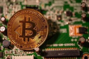 gold coin BTC cryptocurrency on circuit board in concept of crypto minning photo