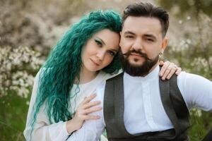 a bearded groom plays a stringed instrument and a girl sits in a spring meadow photo