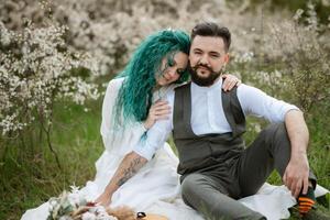 a bearded groom plays a stringed instrument and a girl sits in a spring meadow photo