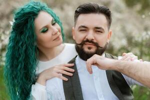 a bearded groom plays a stringed instrument and a girl sits in a spring meadow photo