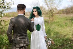 a bearded groom and a girl with green hair dance and twirl photo