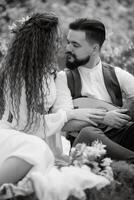 a bearded groom plays a stringed instrument and a girl with sits in a spring meadow photo