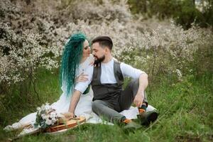 a bearded groom plays a stringed instrument and a girl sits in a spring meadow photo