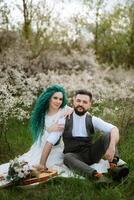 a bearded groom plays a stringed instrument and a girl sits in a spring meadow photo